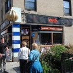 A view from a tour participants perspective of the outside of Sultan's Market. With a gold-domed entrance, blue and white pillar and a black/red logo.